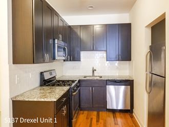 an empty kitchen with black cabinets and stainless steel appliances