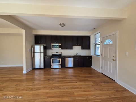 an empty kitchen with black cabinets and a wooden floor