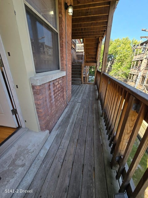 a view of the front porch of a brick house with a wooden deck