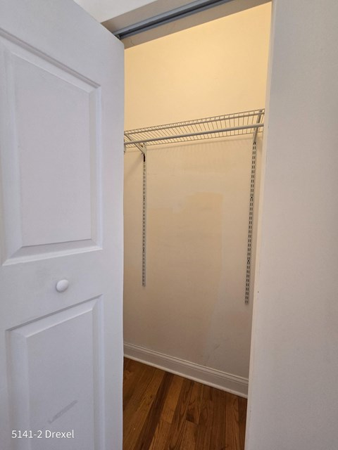 a walk in closet with a white door and a hanging rack on the wall