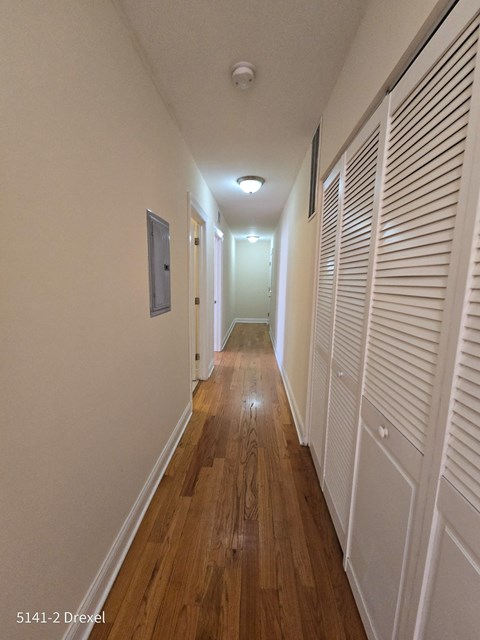 a long hallway with closets on both sides and a wood floor