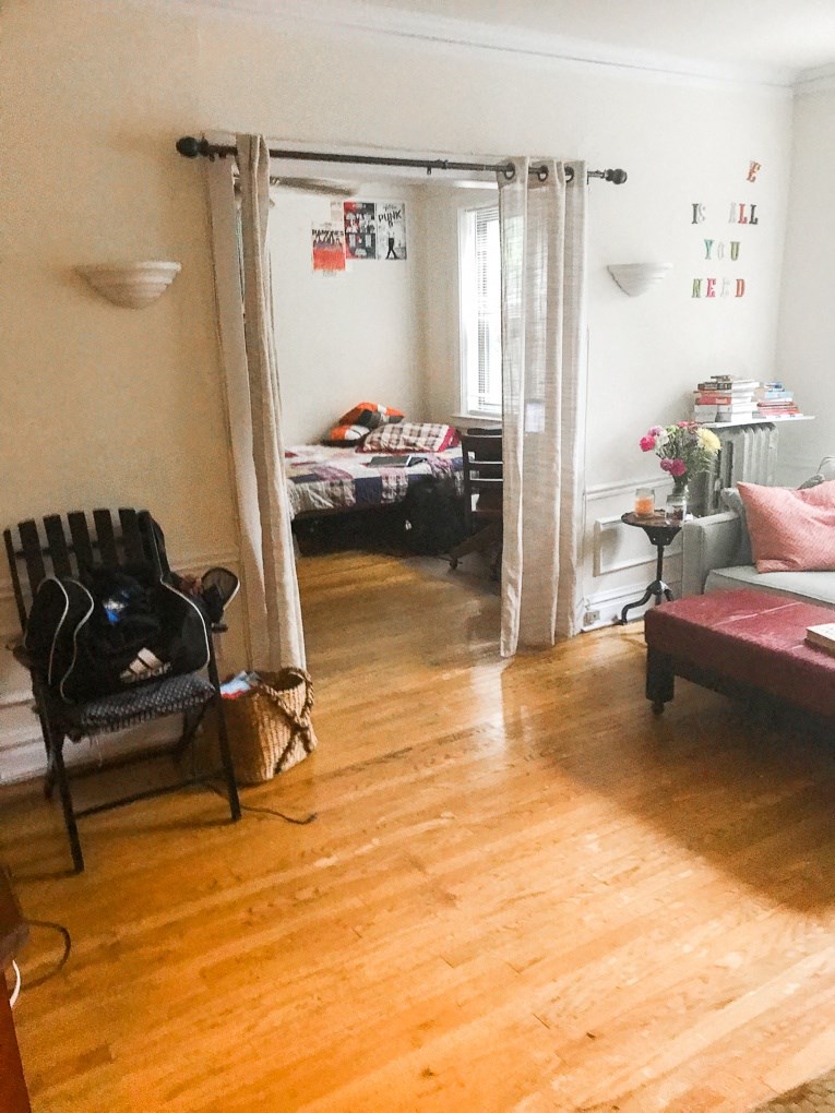 a living room with wooden floors and a bedroom with beds