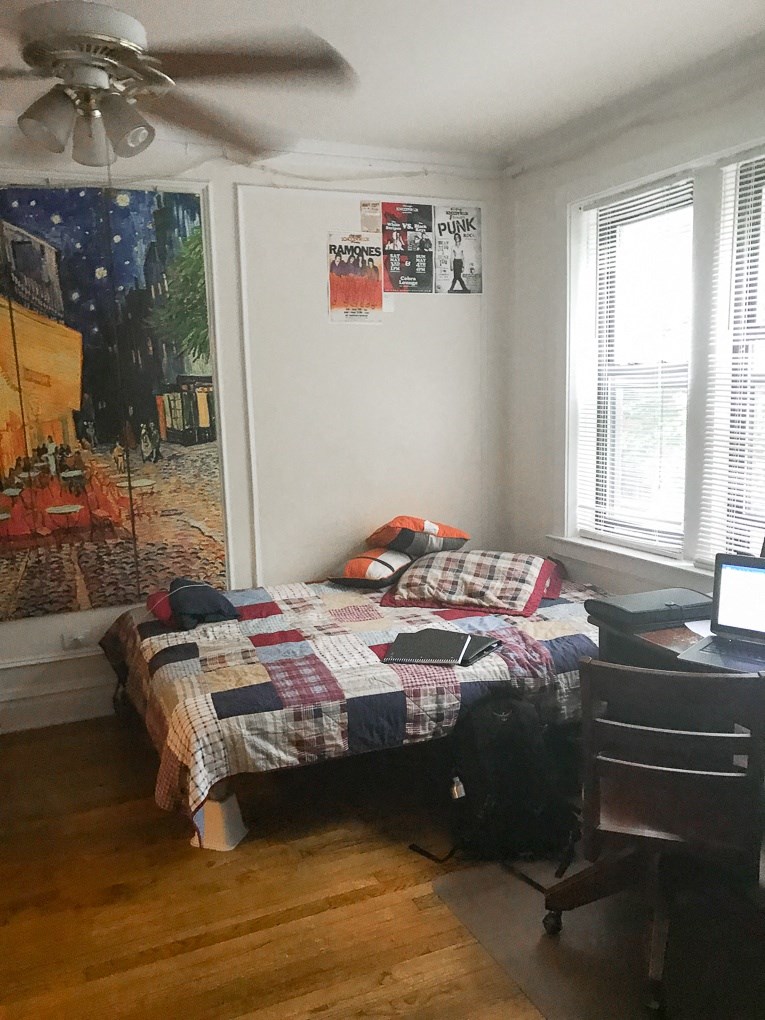 a bedroom with a bed and a desk and a painting on the wall