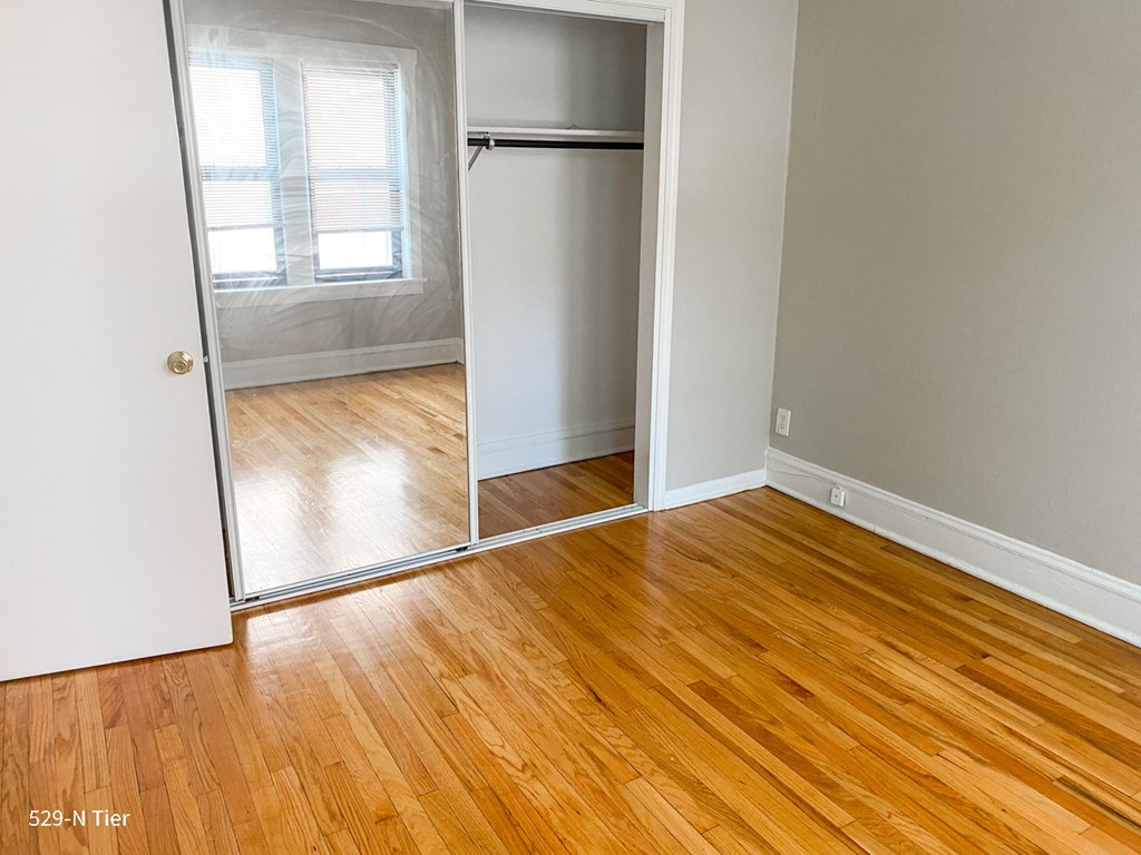 an empty room with wood floors and a closet