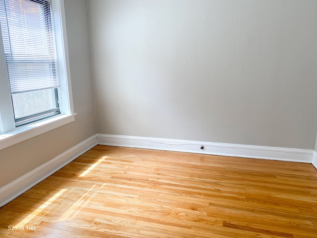 an empty room with wooden floors and a window