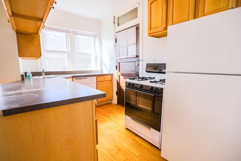 A kitchen with a white refrigerator and a black countertop.