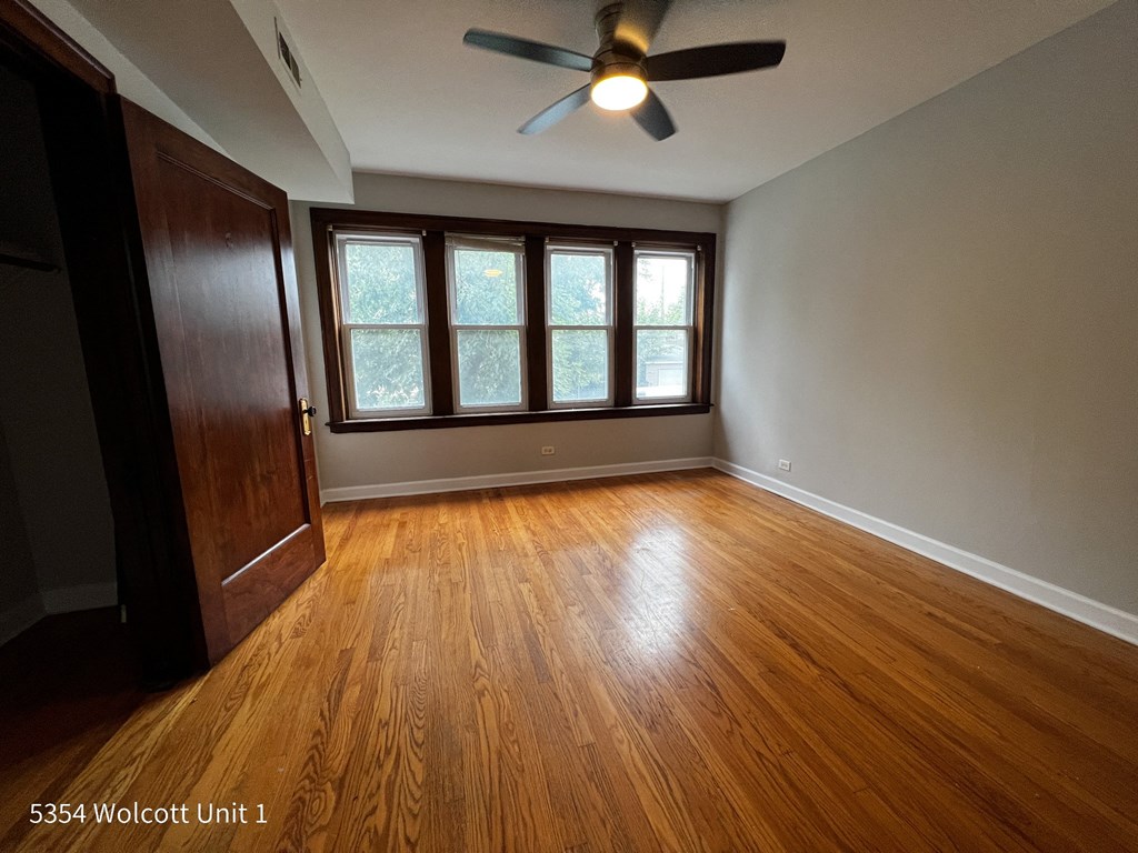 an empty living room with hardwood floors and a ceiling fan