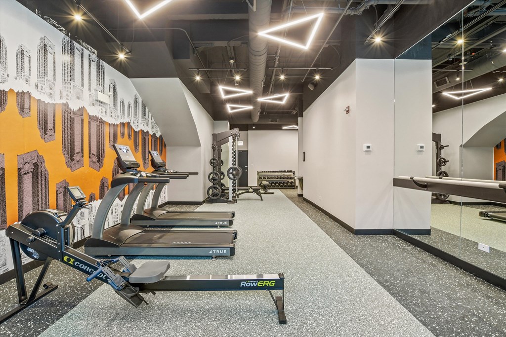 a row of cardio machines in a gym with yellow and white walls