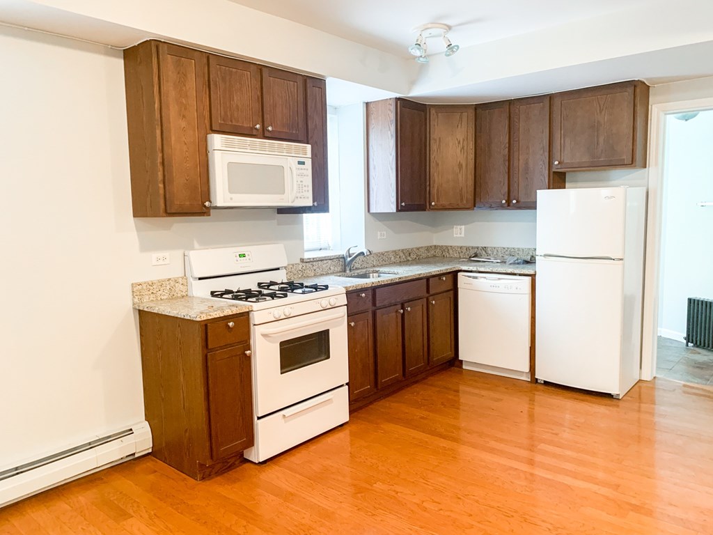 A kitchen with white appliances and wooden cabinets.