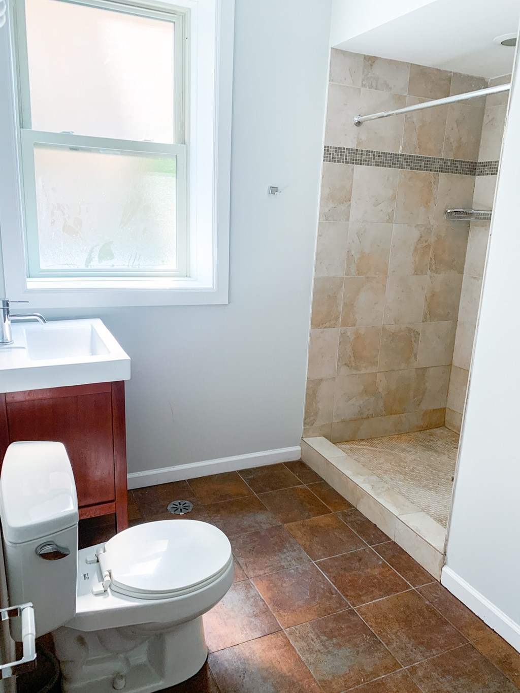A bathroom with a toilet, sink, and tiled shower.