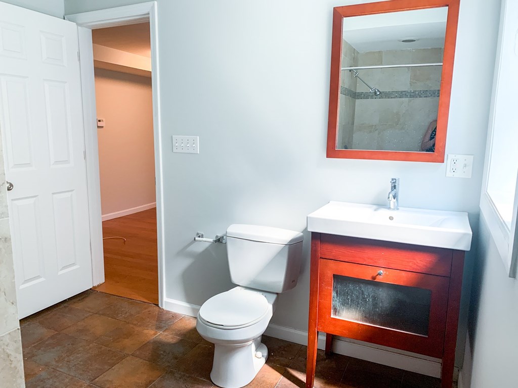 A bathroom with a toilet, sink and mirror.