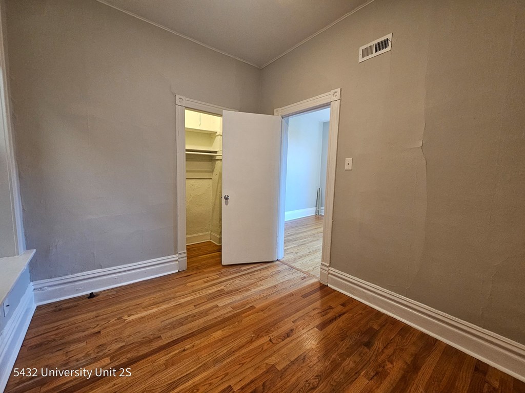 the living room of an empty house with wooden floors and a door to the bathroom