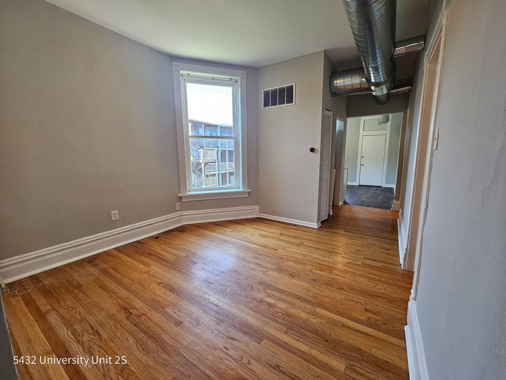 an empty living room with wood floors and a window