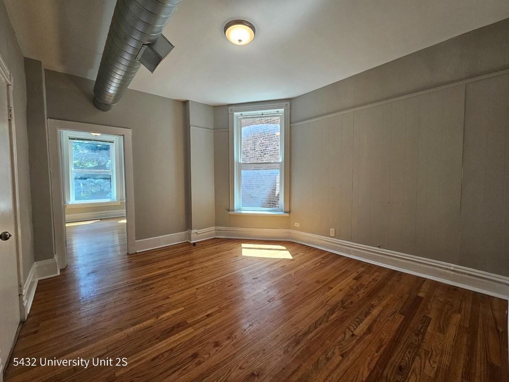an empty living room with wood floors and a window