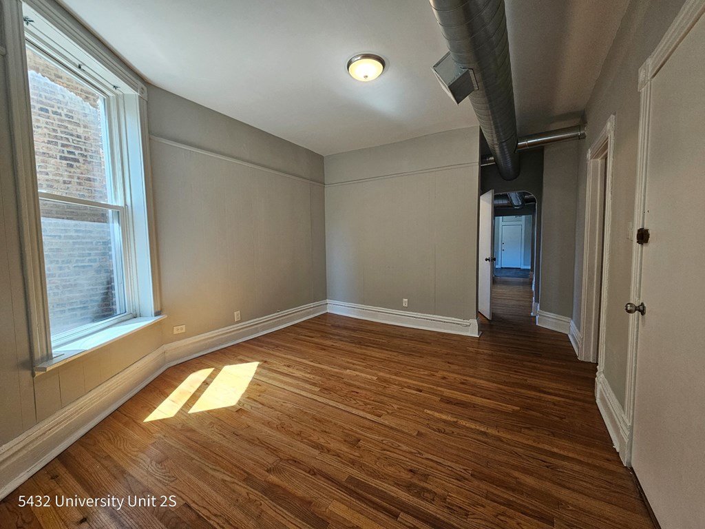 an empty living room with wood flooring and a large window