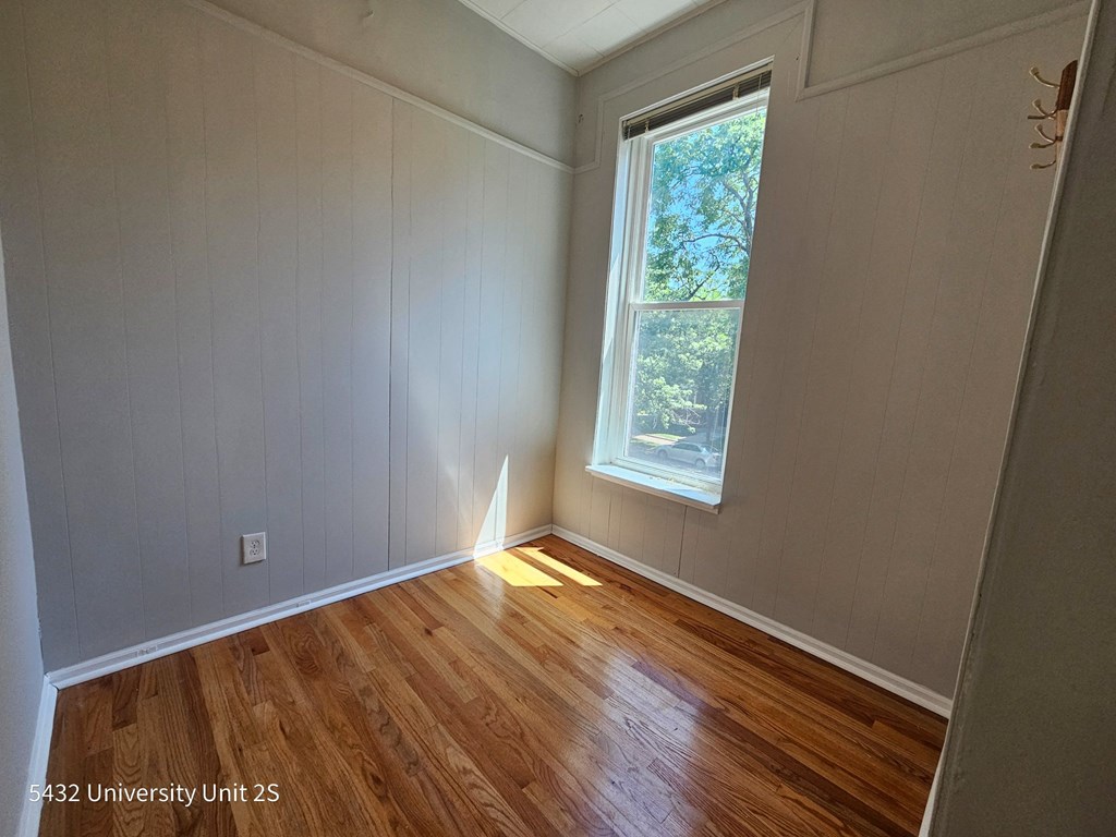 the bedroom of a house with wood floors and a window
