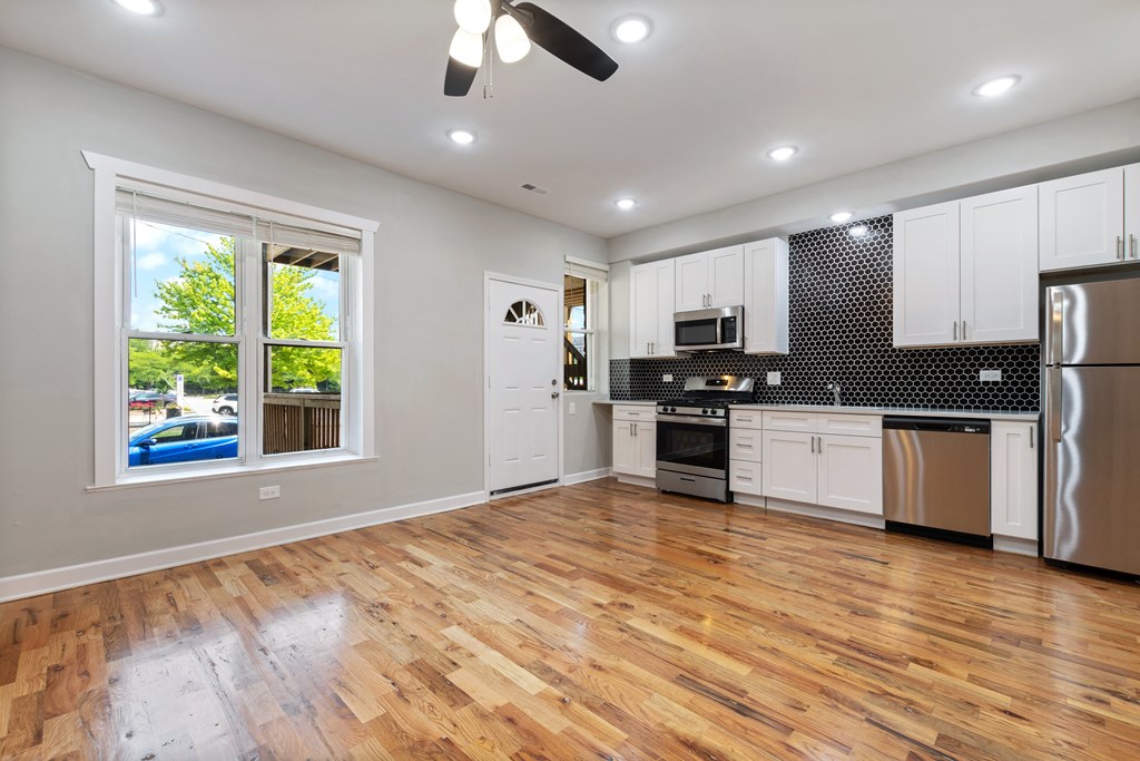 an empty kitchen with a hardwood floor and white cabinets