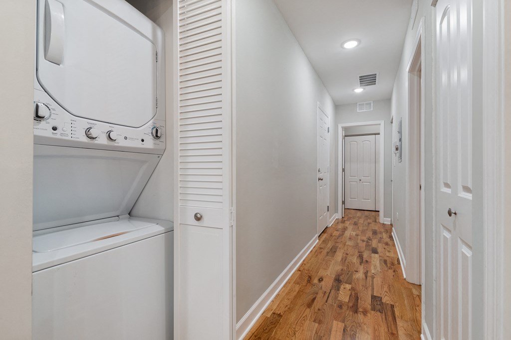 a laundry room with a washer and dryer and a hall to a closet