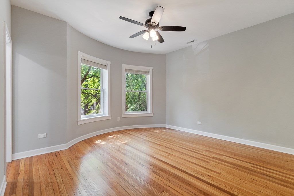 an empty living room with wood floors and a ceiling fan