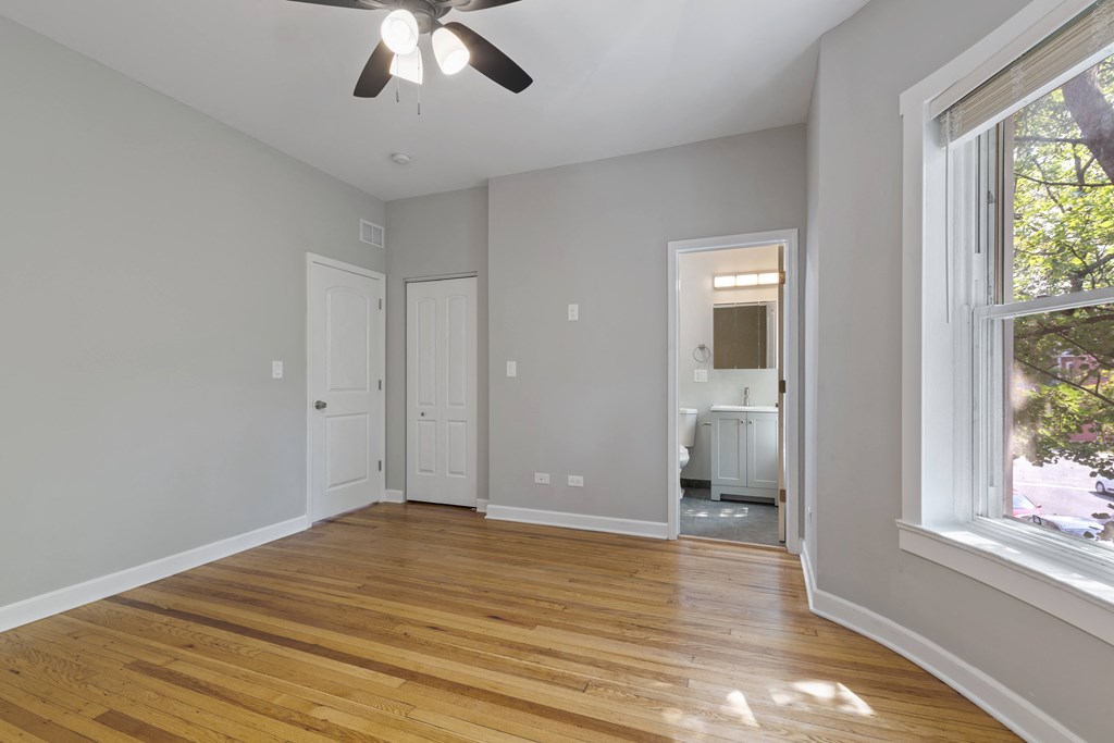 an empty living room with a ceiling fan and a large window