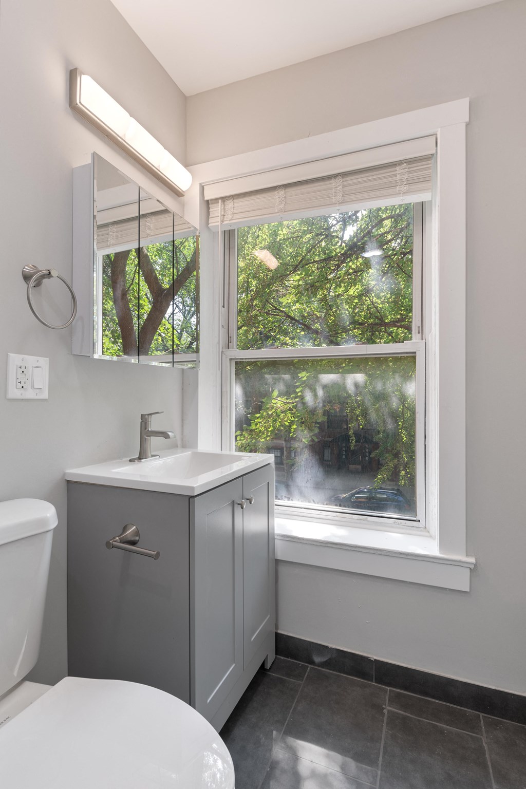a bathroom with a window and a sink and a toilet