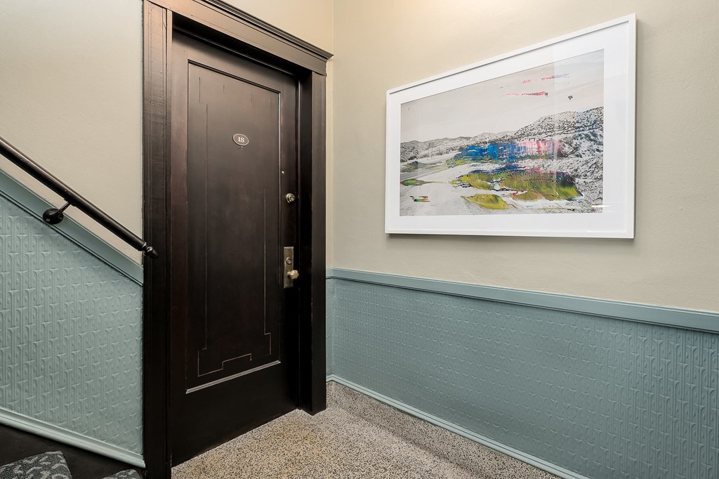 a door leading to a hallway with a painting on the wall