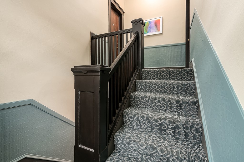 a stairwell with a wooden railing and carpeted stairs