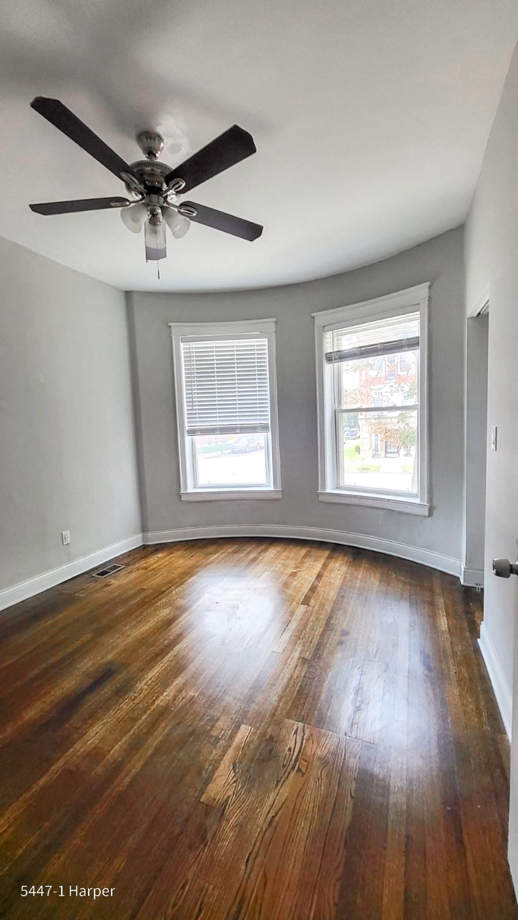 an empty room with a ceiling fan and two windows