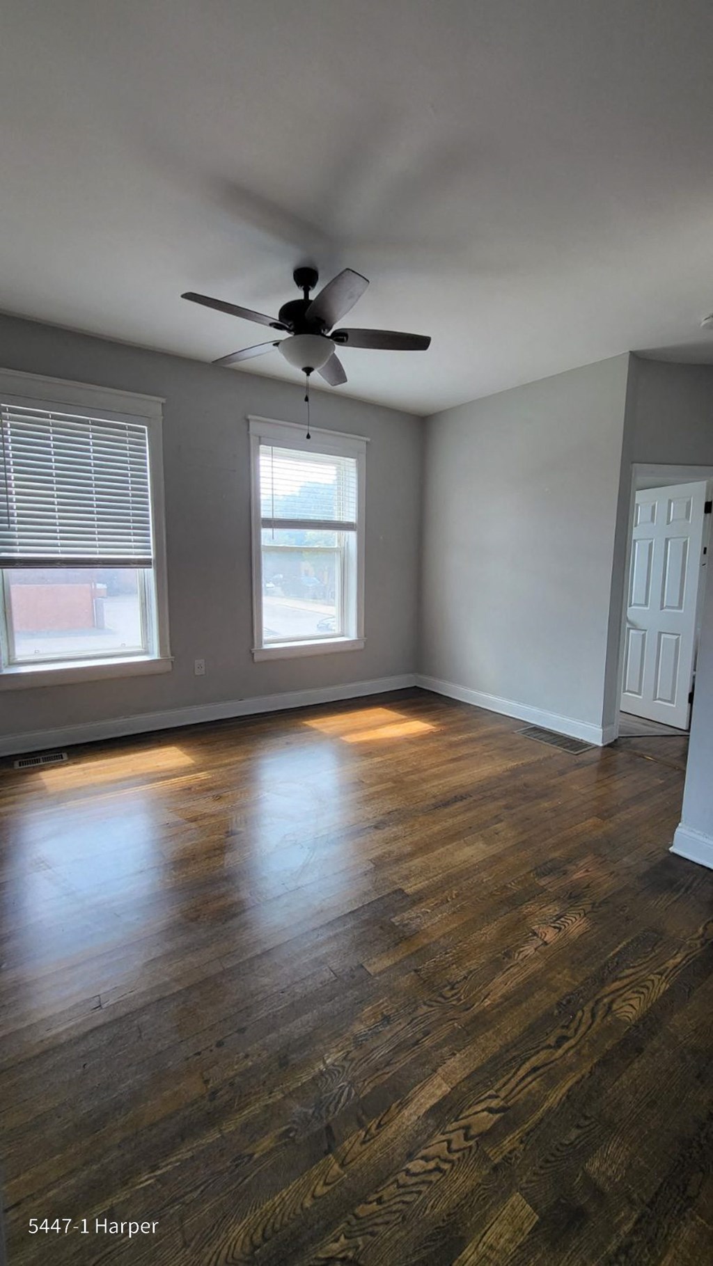 an empty living room with wood floors and a ceiling fan