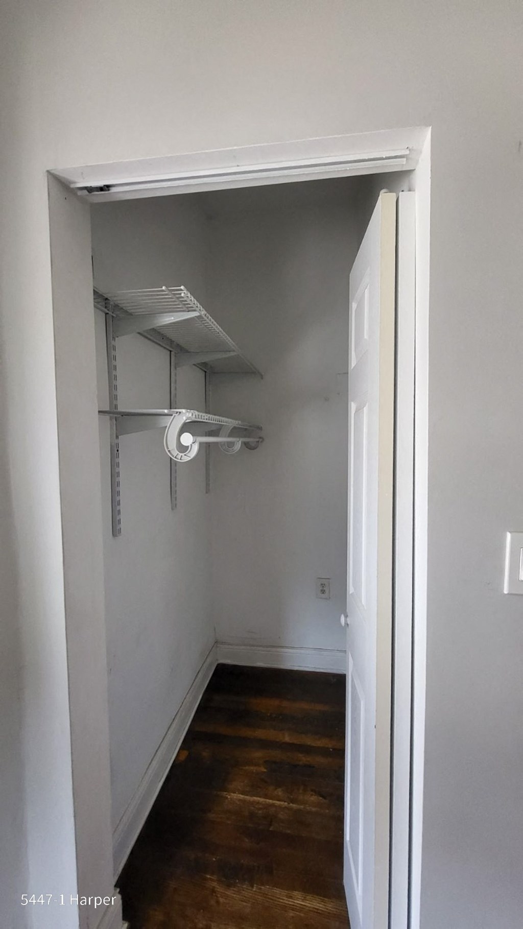 a closet in a small room with a wood floor and a white door