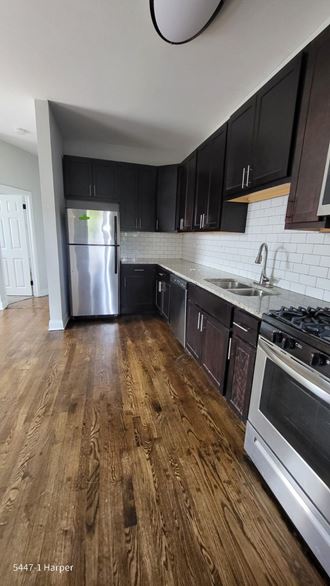a kitchen with wood floors and black cabinets and stainless steel appliances
