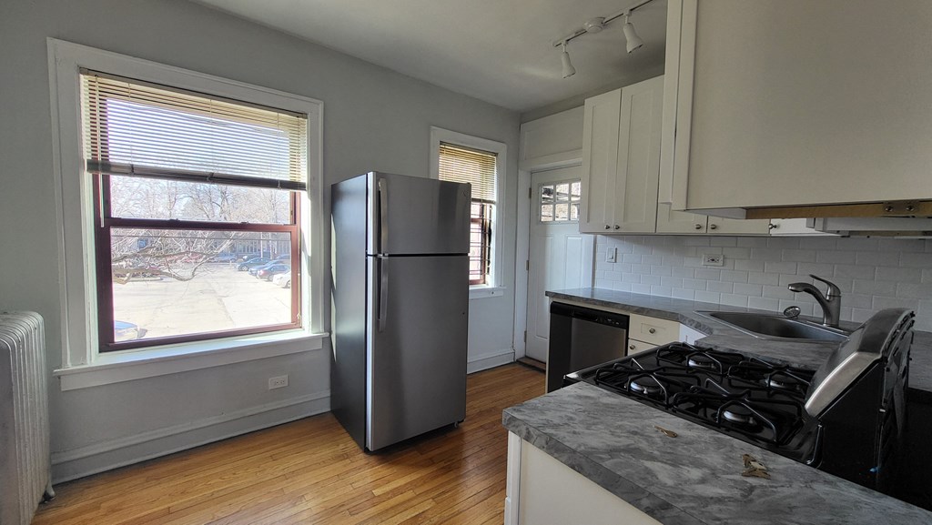 an empty kitchen with a refrigerator and a window