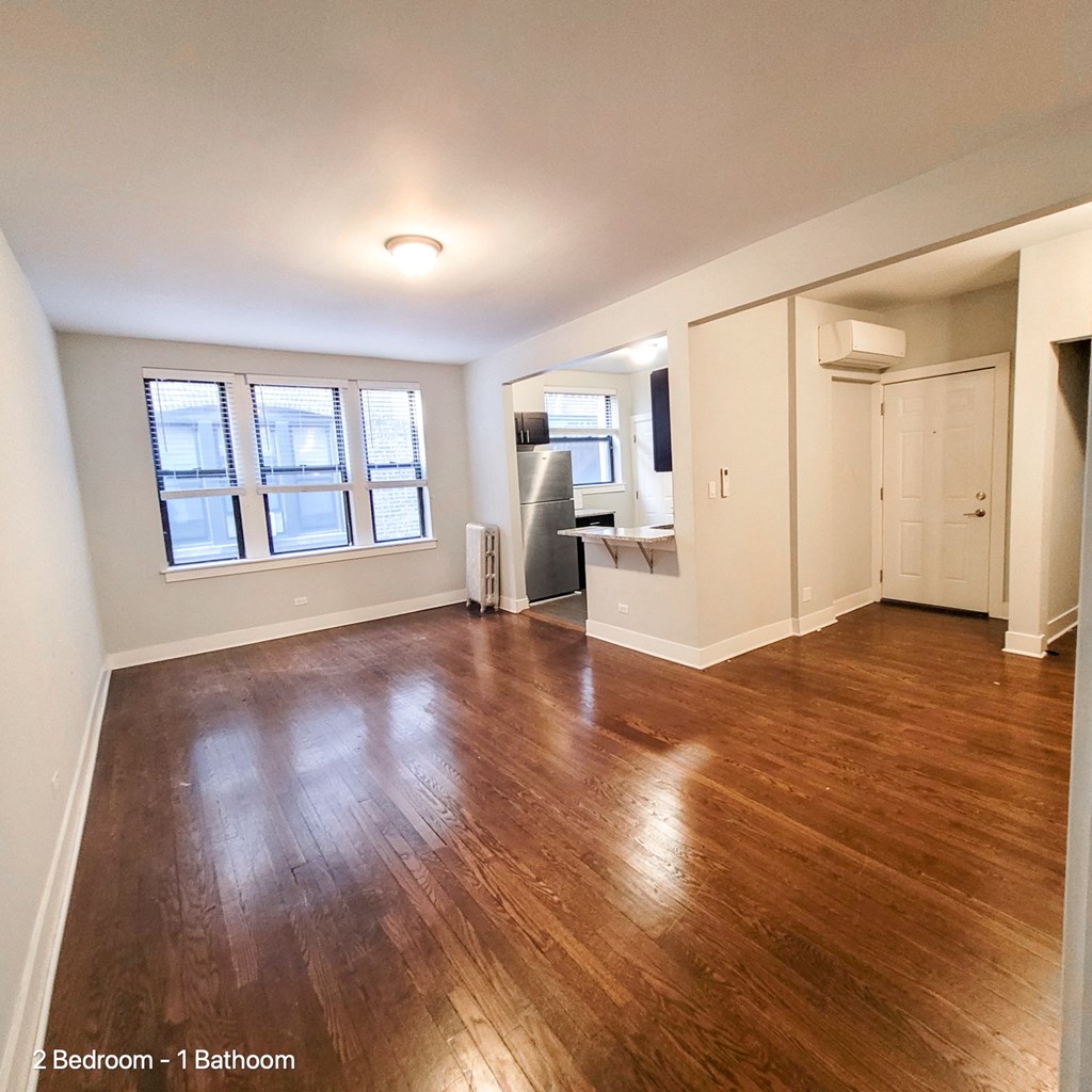 an empty living room with a hard wood floor and a window