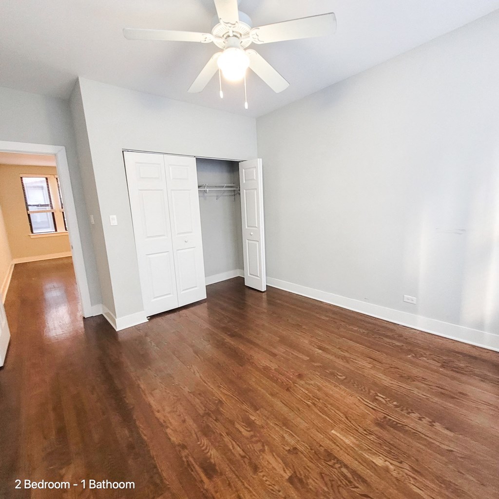 an empty living room with wood floors and a ceiling fan