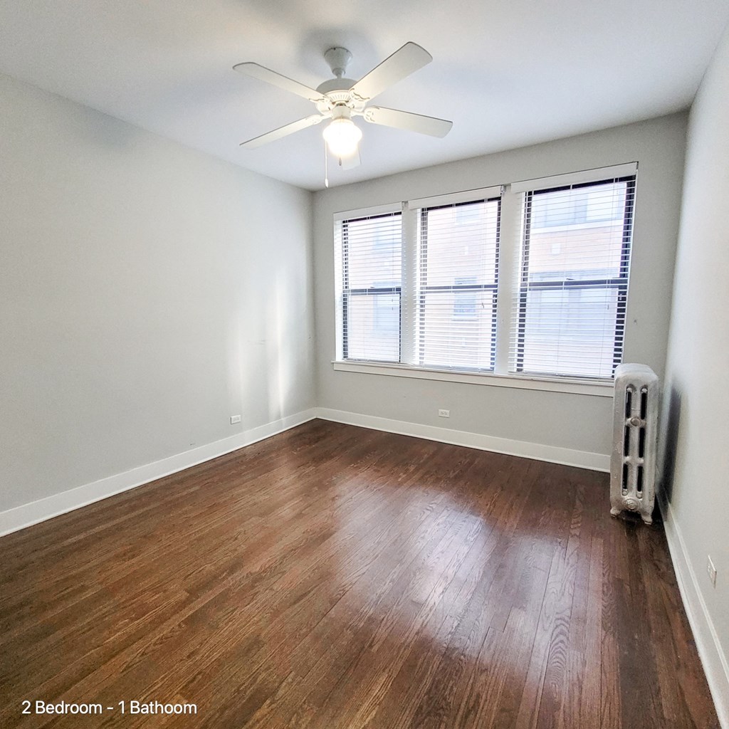 an empty living room with wood floors and a ceiling fan