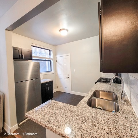 a kitchen with granite counter tops and a stainless steel refrigerator