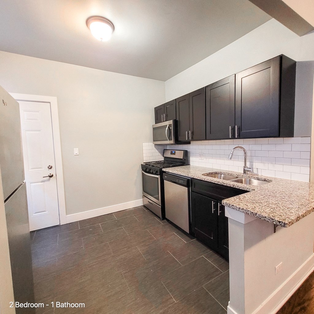an empty kitchen with black cabinets and a counter top