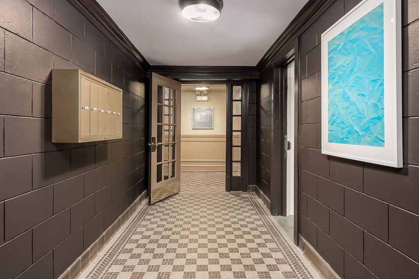 a hallway with brown tiles and a blue painting on the wall