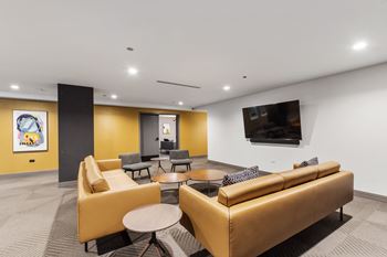 A WiFI lounge room filled with modern yellow sofas, round coffee tables, and a flat screen tv
