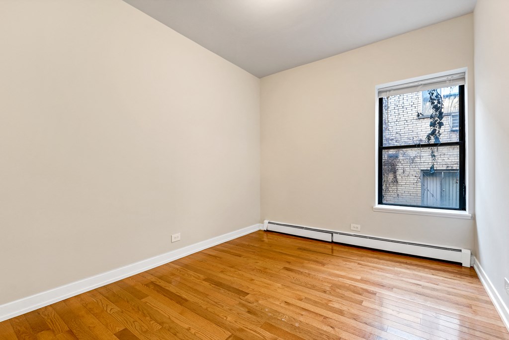 an empty living room with wood floors and a window