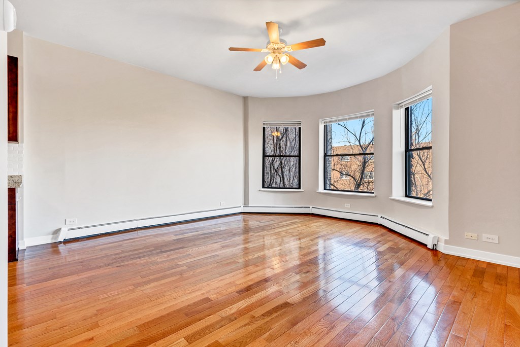 an empty living room with hardwood floors and a ceiling fan