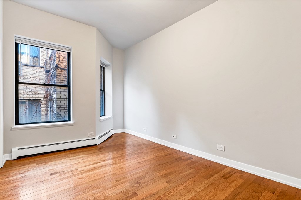 an empty living room with wood floors and a window