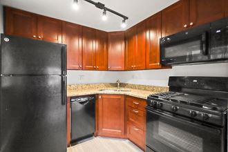 an empty kitchen with black appliances and wood cabinets