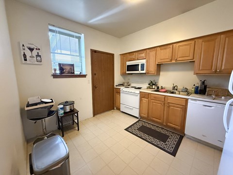A kitchen with white appliances and wooden cabinets.