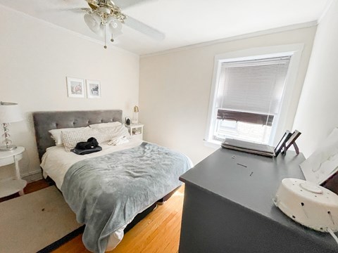 A bedroom with a bed, nightstand, and window.
