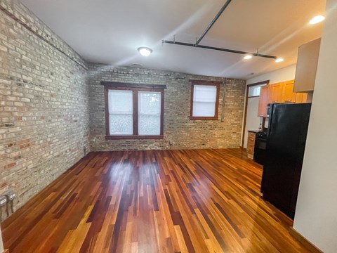 A room with wooden floors and a brick wall.