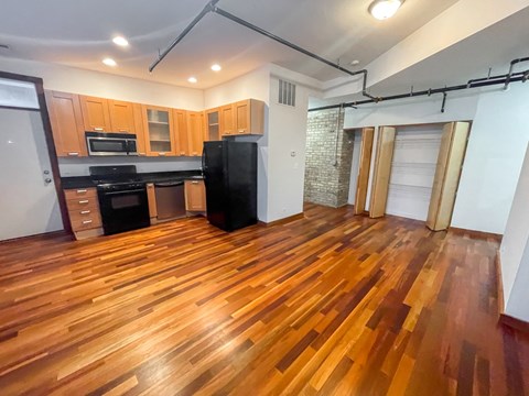 A kitchen with wooden floors and a black refrigerator.
