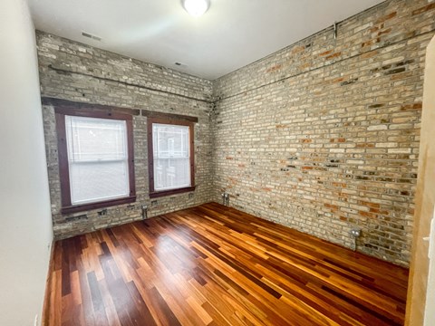 A room with wooden floors and a brick wall.