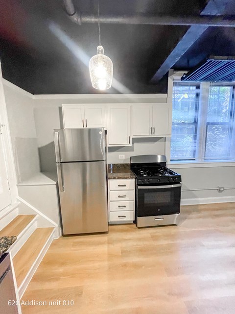 a kitchen with white cabinets and a stainless steel refrigerator