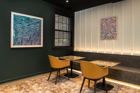 a dining room with two tables and chairs and two paintings on the wall
